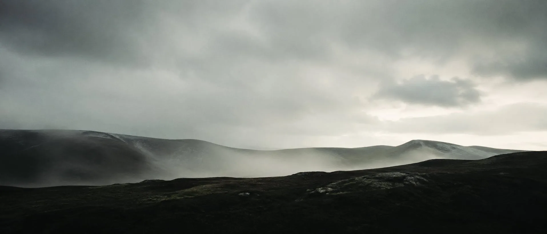 A quiet northern ridge in low winter light, mist settling across the valley below a wide, clean horizon.