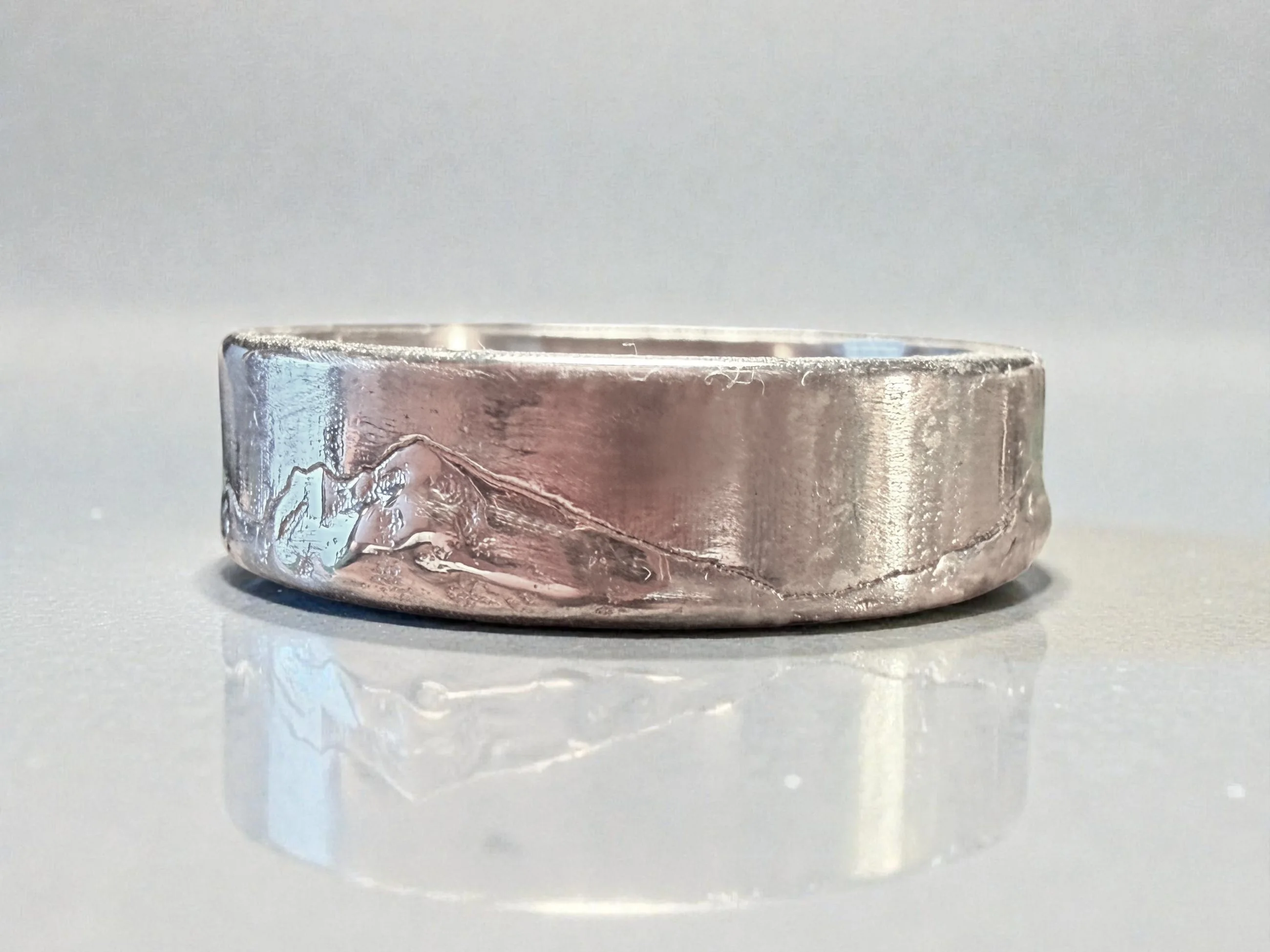 Close view of the band face, with the polished ridge lit above the textured slopes.