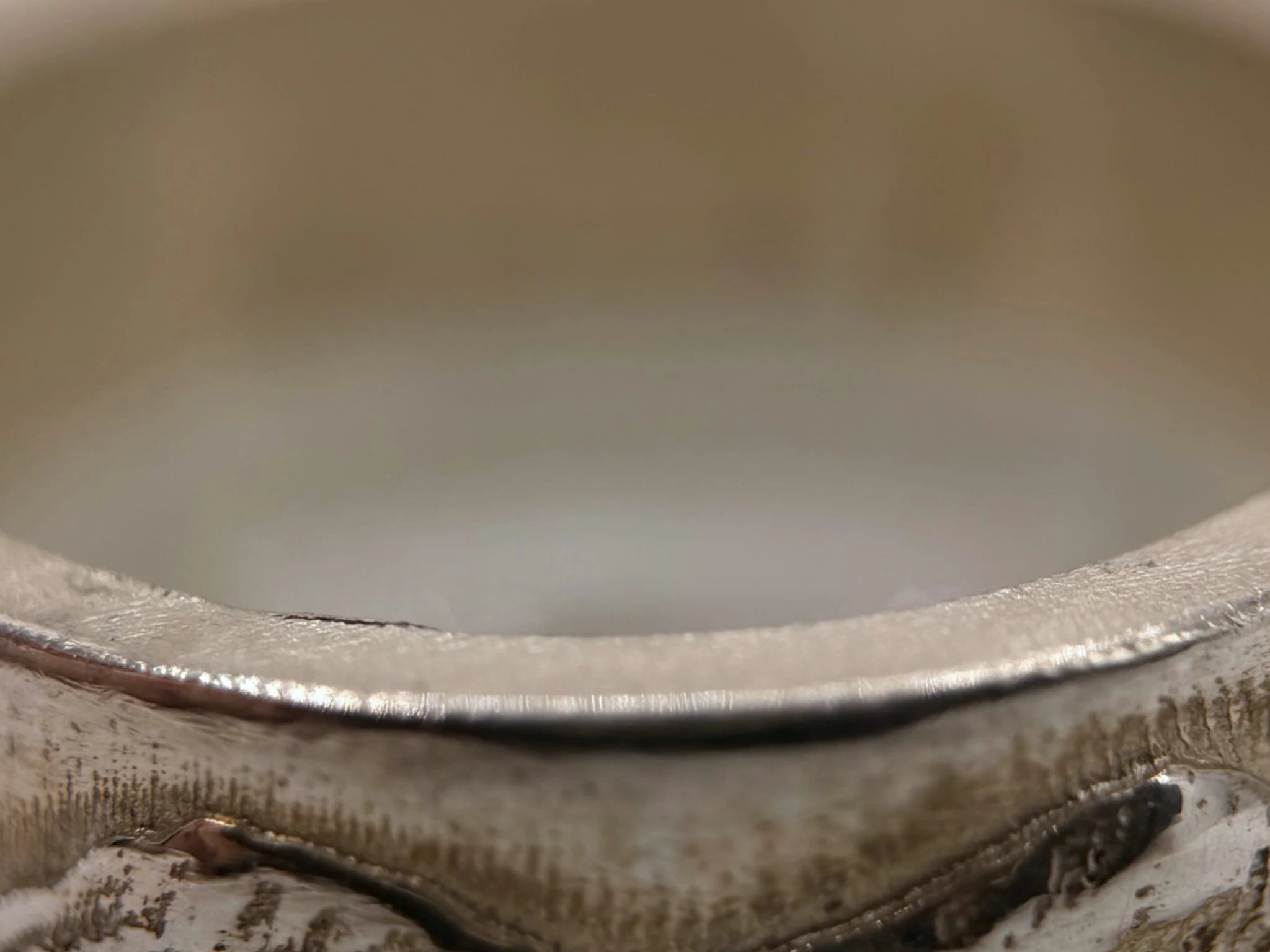 Macro view of the smooth polished interior edge, with the cast outer surface below it.