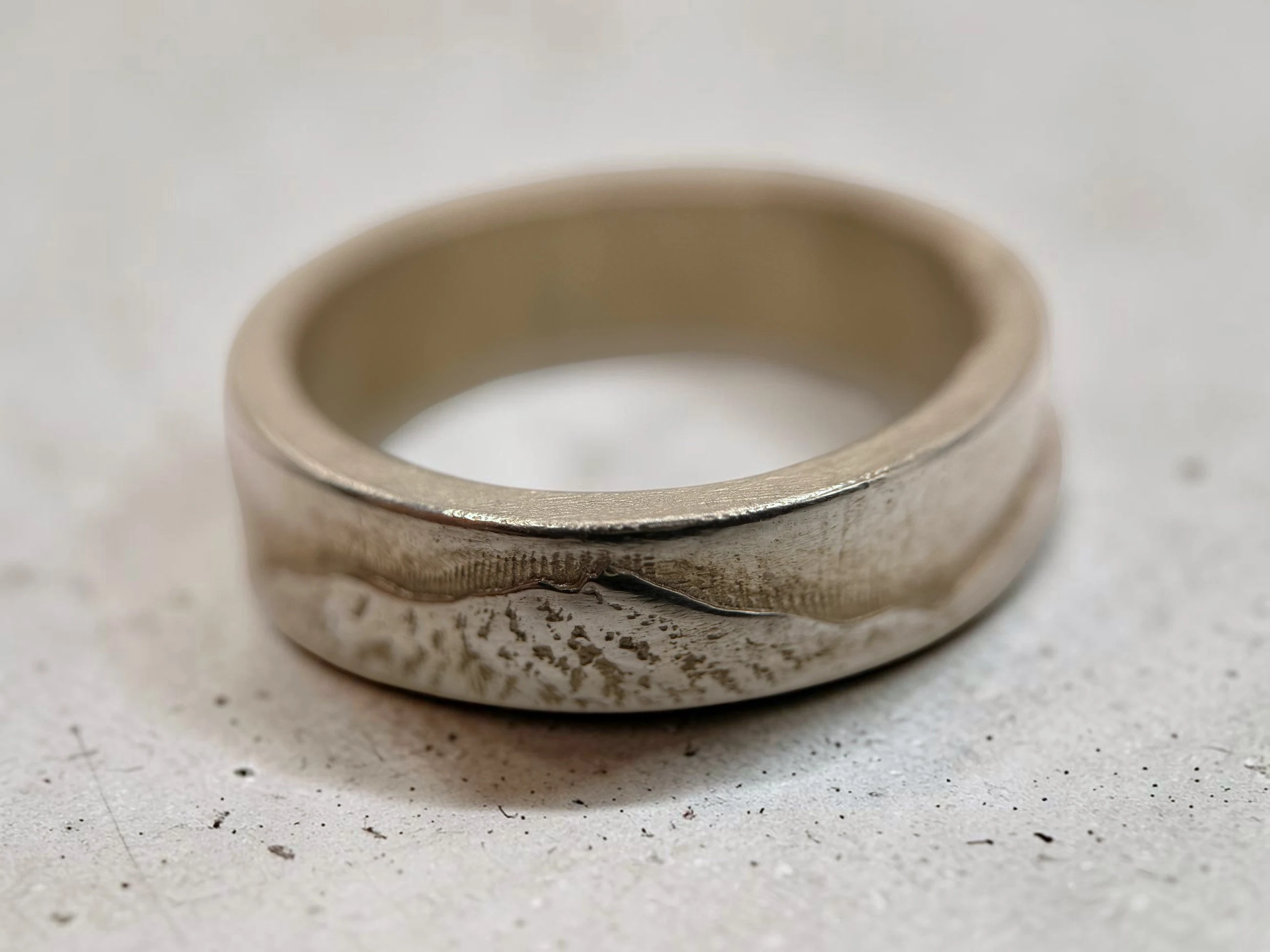 Closer view of the same band, showing the stippled cast slope below the polished ridge.