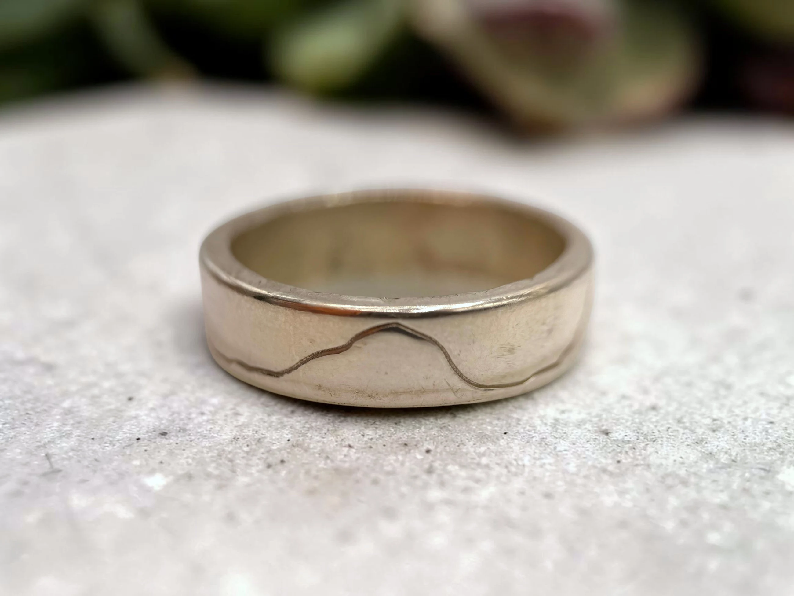 The band turned so the highest point of the engraved line sits centred on the face.