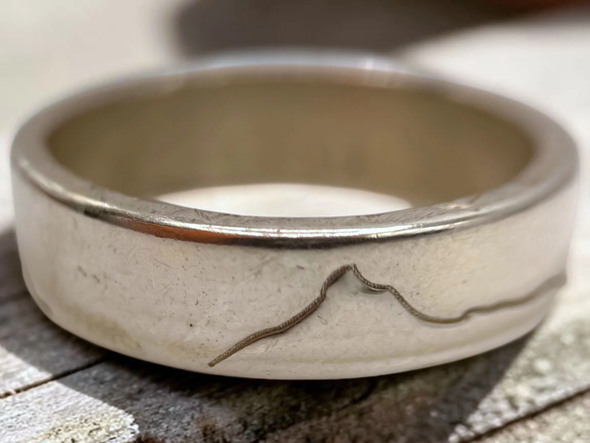 Macro view of the engraved ridgeline, showing how shallowly the line is cut into the silver.